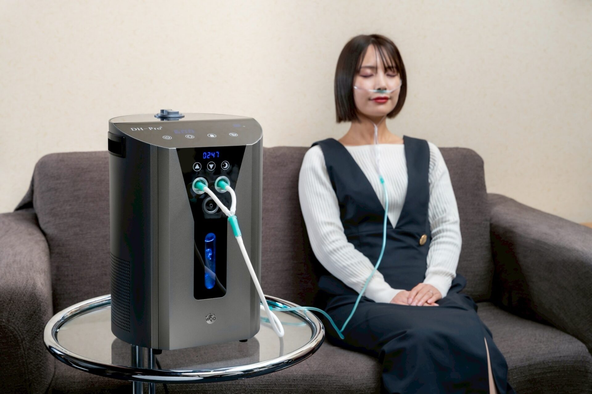 水素ガス吸入機器の隣のソファに座る女性(吸入の体験イメージ)